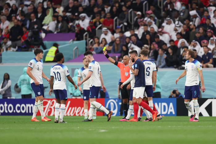 Referee Wilton Sampaio pictured showing a yellow card to Harry Maguire (left) during the 2022 World Cup quarter-final between England and France